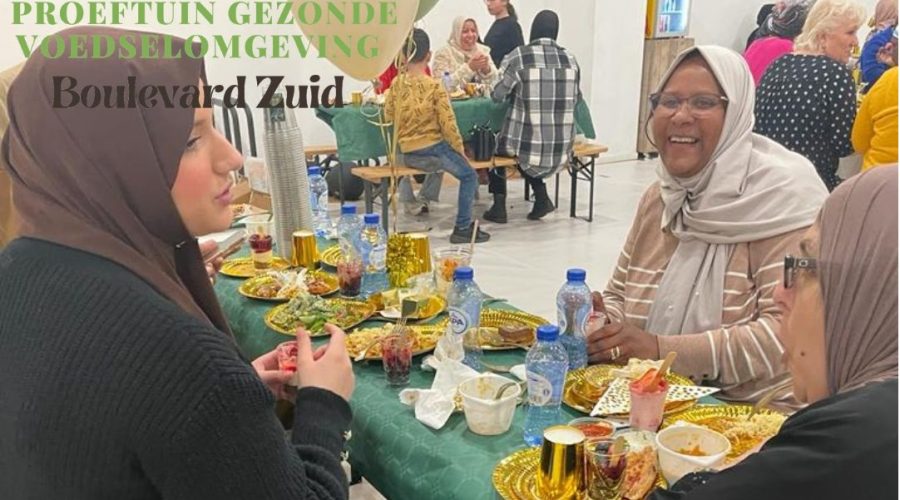 Een foto van mensen die de iftar nuttigen aan een lange tafel.