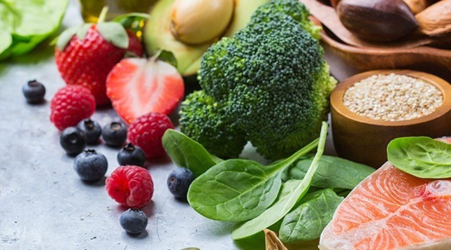Gezonde voeding op een aanrecht, waaronder aardbeien, broccoli en zalm