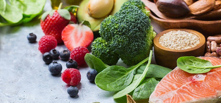 Gezonde voeding op een aanrecht, waaronder aardbeien, broccoli en zalm