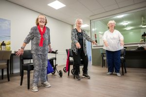 Drie ouderen die beweegoefeningen doen